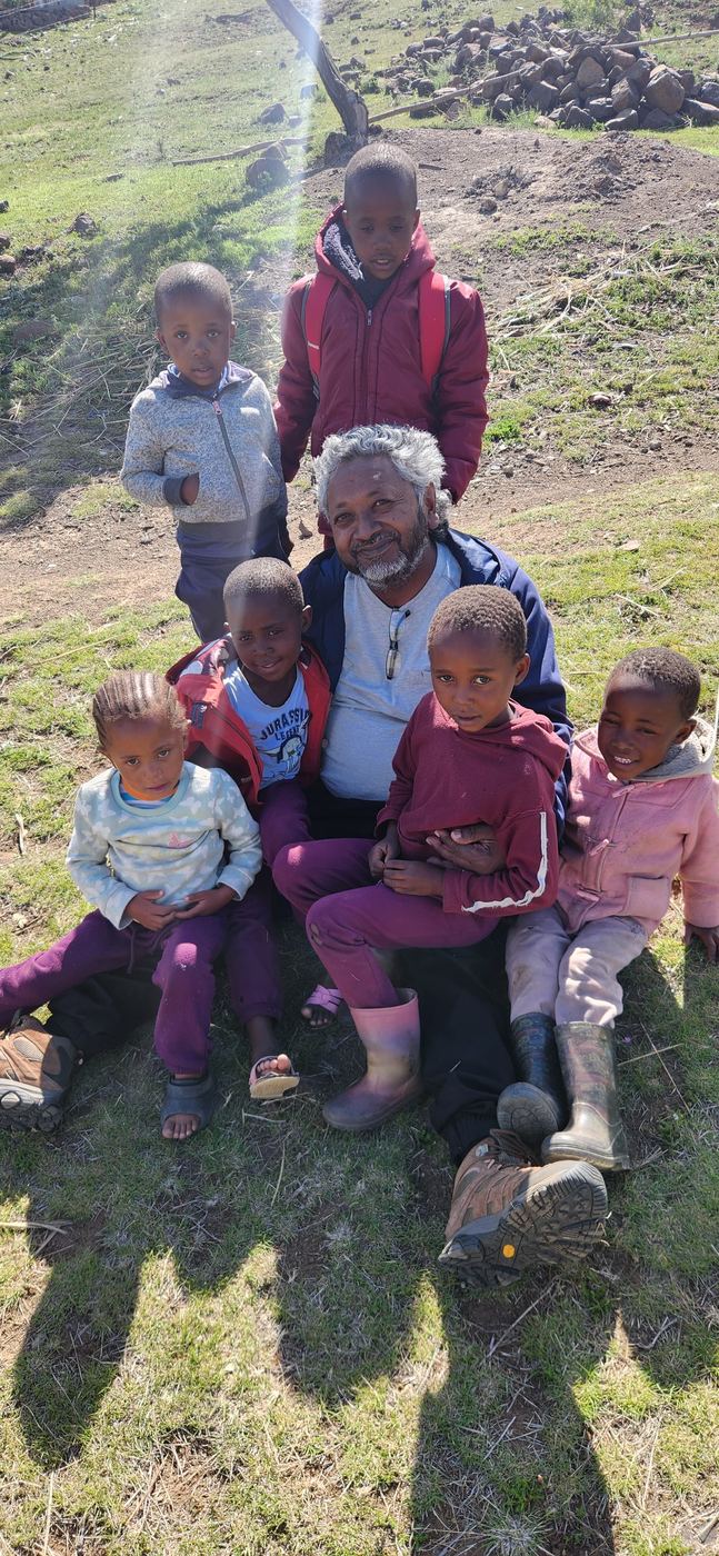 An elder sitting with children on a hillside in Lesotho