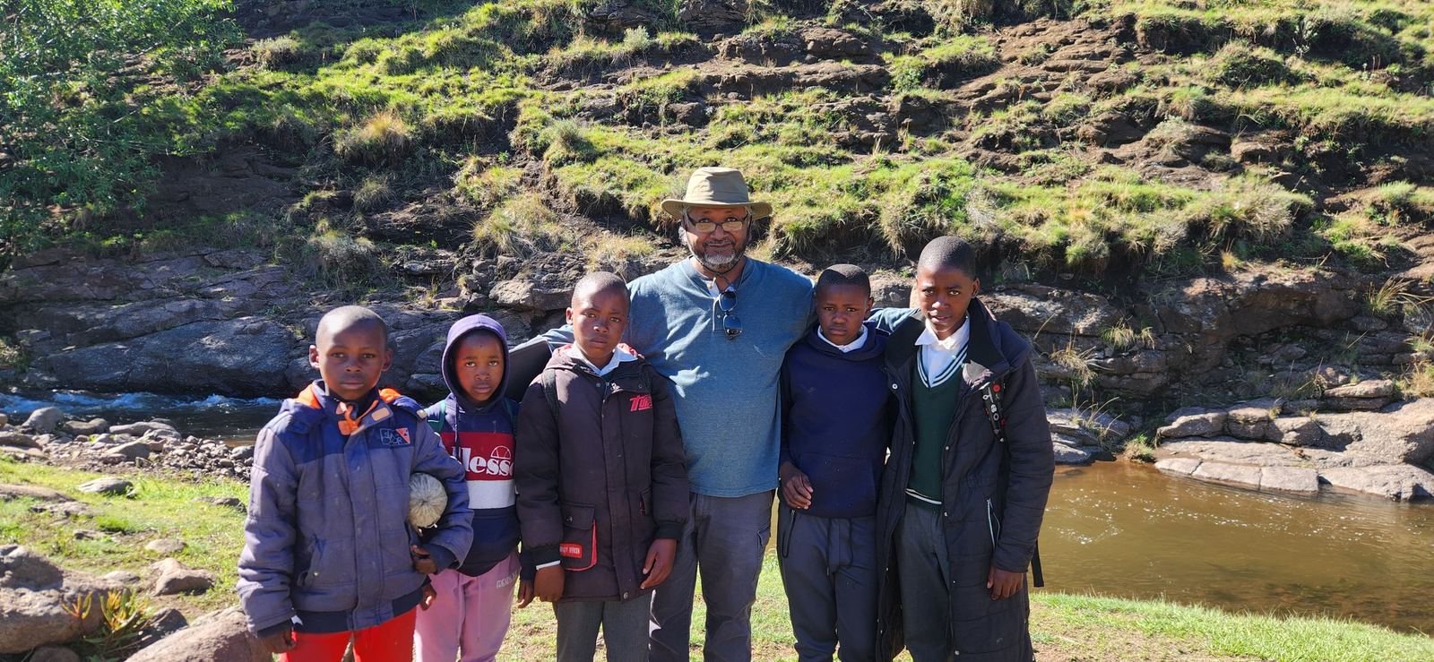 A Dominion team with a group of children and adults by a river in Lesotho
